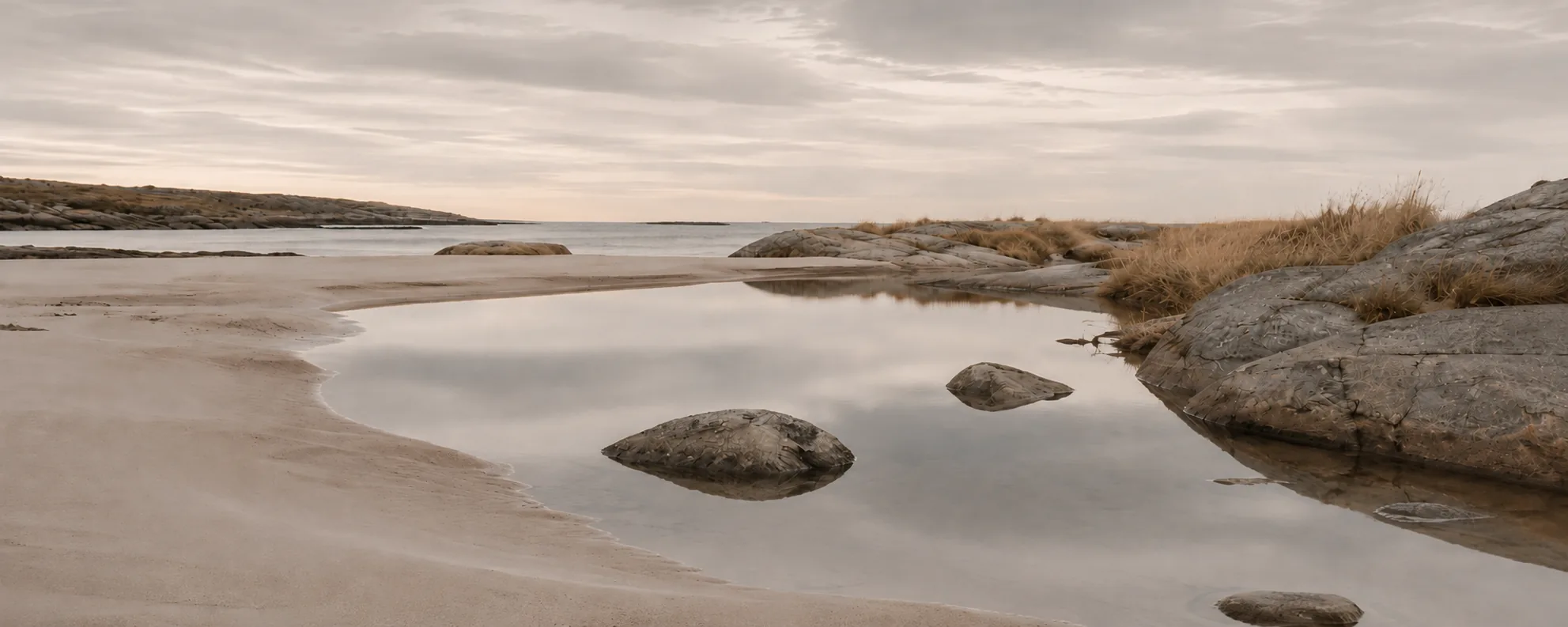 Rolig kystlandskap med sand og svaberg